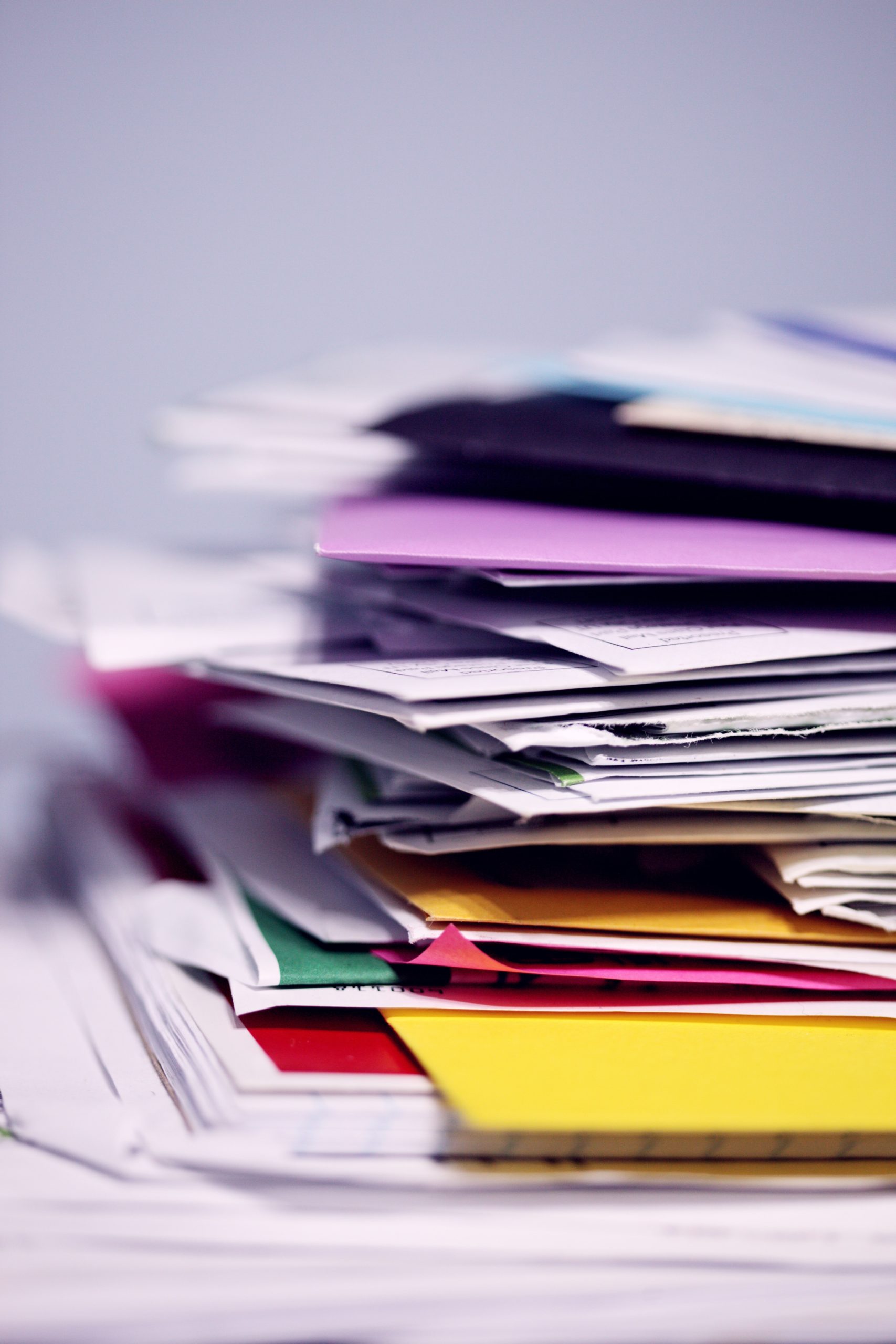 Messy stack of papers and documents falling out of multi-colored file folders